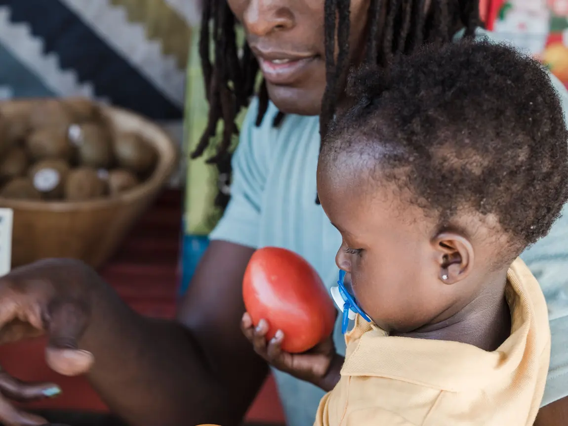 A parent and toddler sorting fruit together.